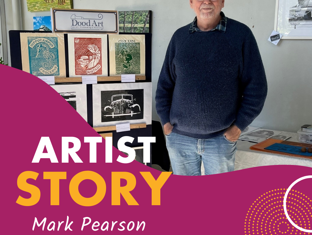 A photo of Mark Pearson, standing proudly next to a collection of his artworks.