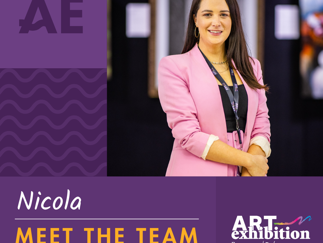 The 2024 exhibition curator is Nicola Holly who has mid length brown hair and is wearing a pink suit with a lanyard around her neck.