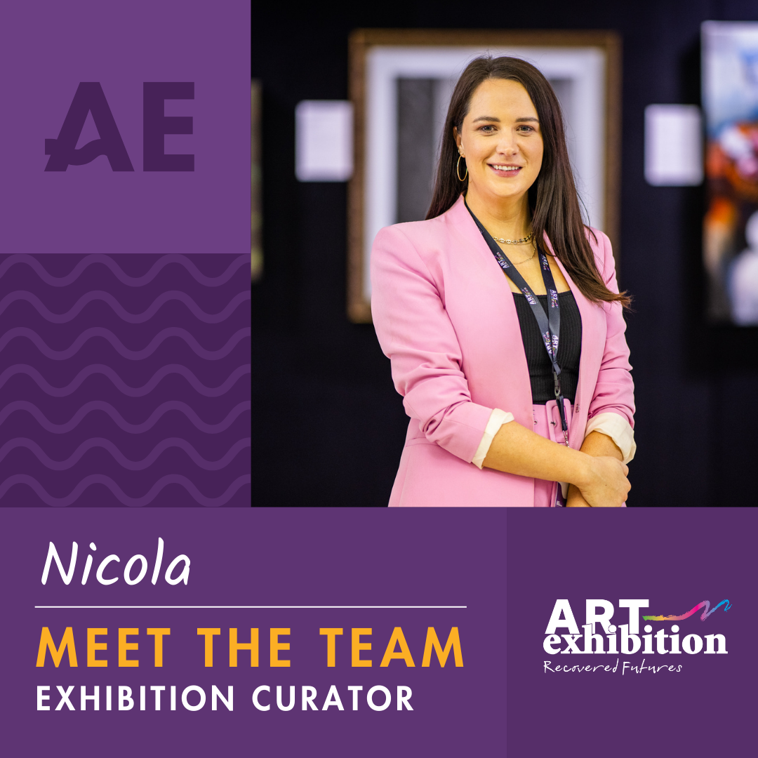 The 2024 exhibition curator is Nicola Holly who has mid length brown hair and is wearing a pink suit with a lanyard around her neck. 